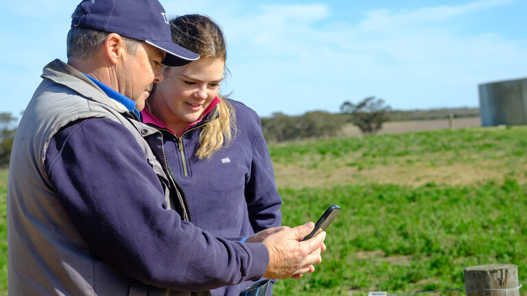 Dvoje farmera pregledavaju podatke o stoci na mobilnoj aplikaciji Tru-Test